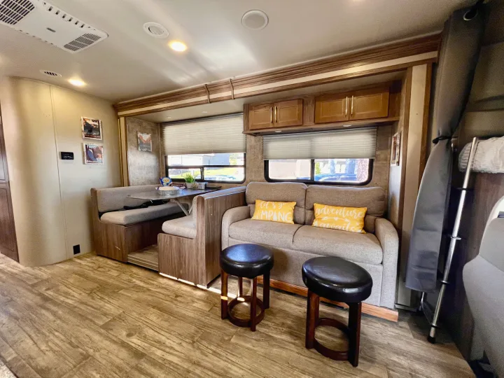 Inside a comfy rv rental, featuring a dinette, sofa with pillows, and modern wood-look floor.. Jayco Envoy 100 2018