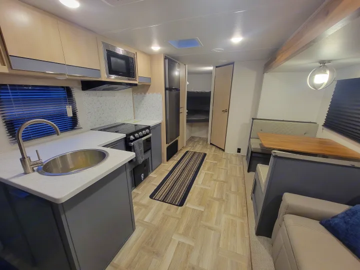 Well-lit rv rental interior with a full kitchen, dining area, lounge space, and bunk beds.. Prime Time Tracer 2700BHSLE 2024