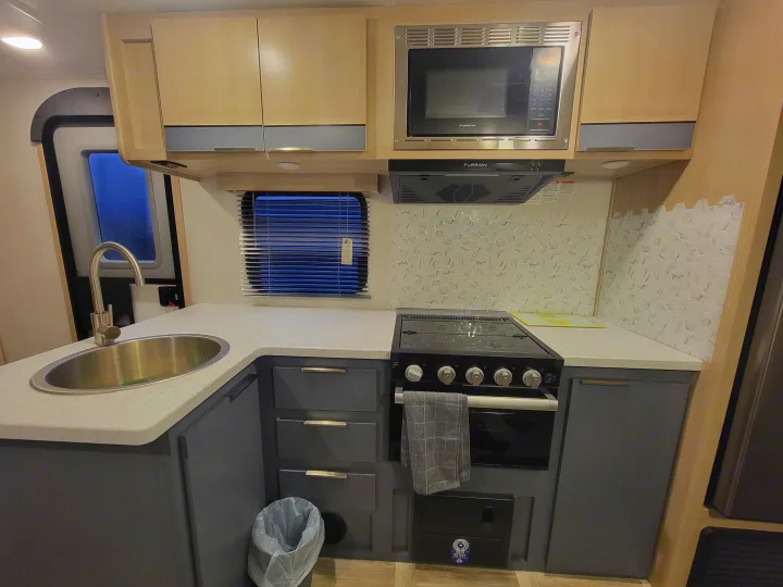 RV rental kitchen: sink, stove, microwave, & modern hex tile backsplash. Fully equipped for travel.. Prime Time Tracer 2700BHSLE 2024