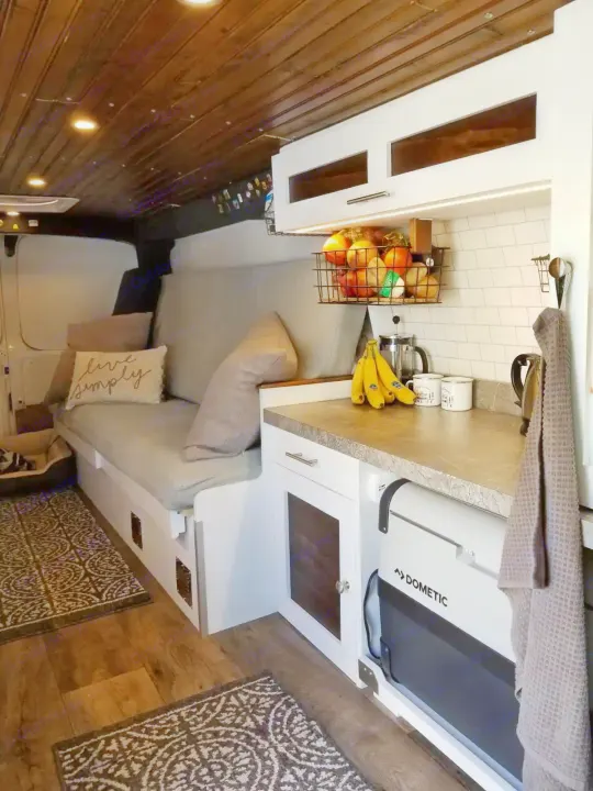 This cozy camper van interior for RV rental features a compact kitchen with Dometic fridge and comfortable living space.. Chevrolet Express 3500 2012
