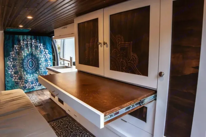 Explore this **RV rental**! A stylish camper van interior with a clever pull-out counter, kitchen, and stunning mandala curtain.. Chevrolet Express 3500 2012