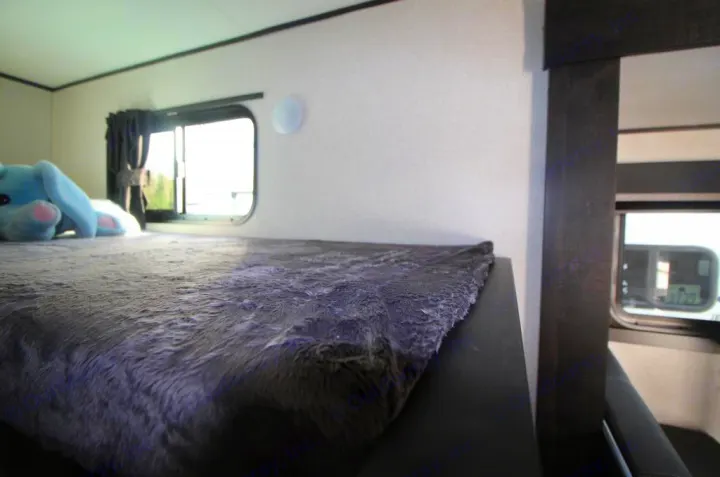 Cozy RV rental bunk bed with plush blanket and stuffed animal, offering a view out the window.. Starcraft Autumn Ridge 180BHS 2023