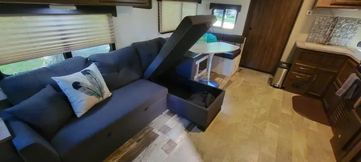 RV rental interior featuring a practical L-shaped sofa with storage, dinette, and kitchen area. Ready for adventures.. Coachmen Apex 265rbss 2019