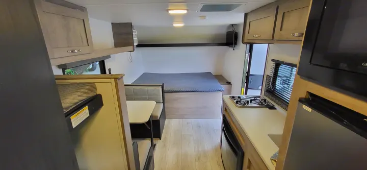 Clean, modern rv rental interior: bed, dinette, kitchen with stove & fridge, and cabinets. Ready for travel!. A Liner Ascape 2024