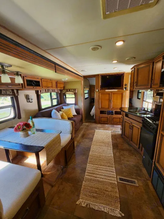 Cozy RV rental interior: dining area, lounge couch, and kitchen. Ideal home on wheels for your next adventure.. Crossroads RV Cruiser 2012