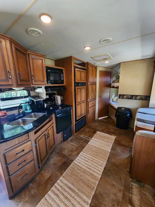 Spacious RV rental interior featuring a full kitchen, dining area, and bunk beds. Perfect for family adventures.. Crossroads RV Cruiser 2012