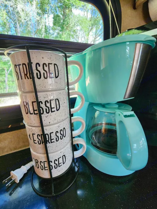 RV rental kitchen counter with a turquoise coffee maker and a stack of 'Stressed, Blessed, Espresso, Obsessed' mugs.. Crossroads RV Cruiser 2012