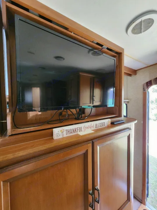 RV rental interior featuring a TV in a wooden entertainment center, with a "THANKFUL Grateful BLESSED" sign below.. Crossroads RV Cruiser 2012