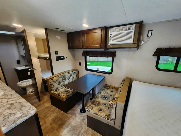This rv rental interior features a dinette, kitchenette, bunk beds, bathroom, and air conditioner, creating a functional space.. Keystone RV Springdale 2018