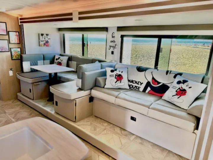 Spacious RV rental interior with a comfy Mickey Mouse themed living area and stunning beach views. Perfect for your next adventure!. Forest River Wildwood 2024