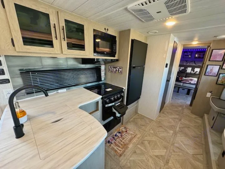 Spacious RV rental kitchen & living area with modern amenities, leading to cozy bunk beds. Perfect for glamping adventures!. Forest River Wildwood 2024