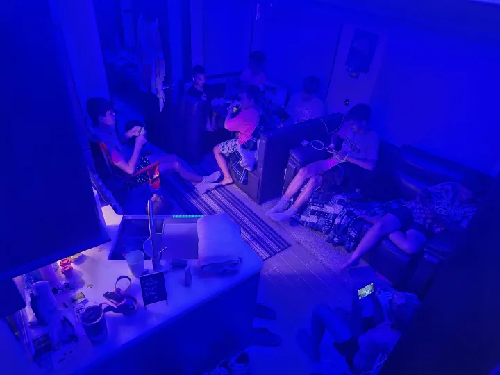Young people relax in a blue-lit RV rental. This cozy motorhome provides a perfect mobile hangout for trips.. Forest River Cherokee Arctic Wolf 2019