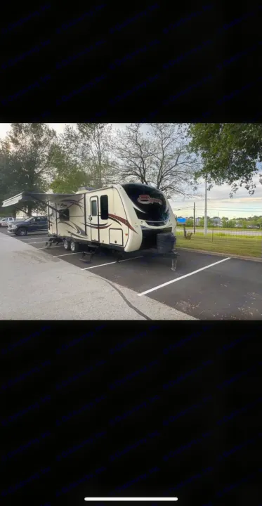 Experience outdoor travel! This cream-colored travel trailer rv rental is parked with its awning extended in an asphalt lot.. KZ Spree 2017