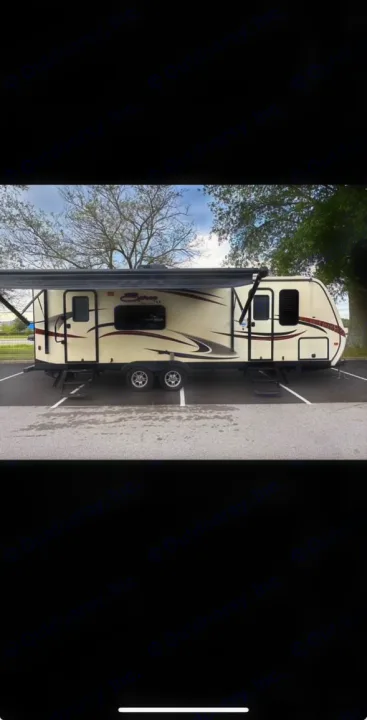 Light-colored travel trailer with awning extended, steps down, parked on asphalt. Ideal for an rv rental experience.. KZ Spree 2017