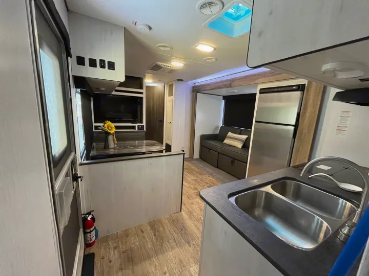 This modern RV rental interior features a functional kitchen with a double sink and an inviting living area.. Heartland RVs Trail Runner 2022