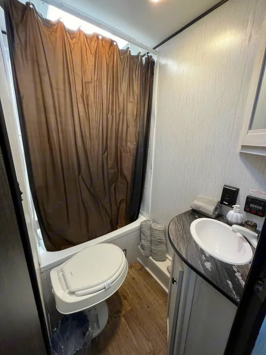 Compact RV rental bathroom: shower/tub, toilet, and vanity with sink. Practical and ready for travel.. Heartland RVs Trail Runner 2022