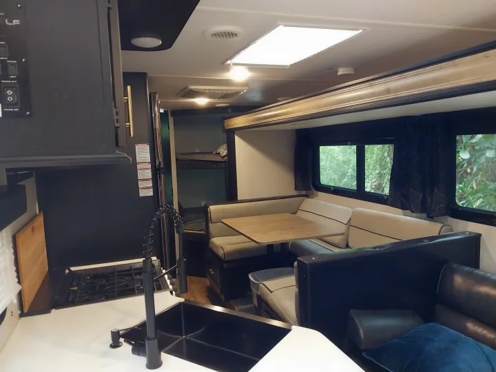 This RV rental interior features a well-appointed kitchen, U-shaped dinette, bunk beds, and comfy sofa in a modern camper design.. Forest River Cherokee Grey Wolf Black Label 2021