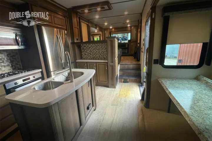Spacious RV rental interior showcasing a modern kitchen with stainless steel appliances, living area, and upscale finishes.. Keystone Montana 2019