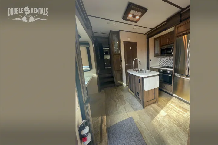 Spacious RV rental kitchen with a modern island, stainless steel appliances, and tiled flooring.. Keystone Montana 2019