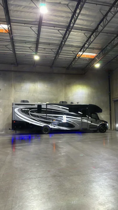 Sleek, dark grey RV with white/black graphics & blue underglow, ready for your next rv rental adventure!. Jayco Seneca 2020