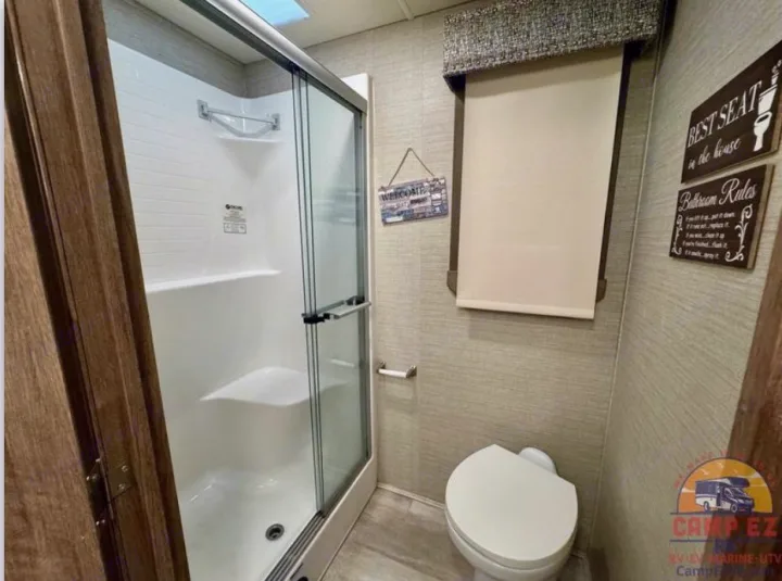 RV rental bathroom with a glass-enclosed shower, compact toilet, and window shade for your comfort.. Jayco Seneca 2020