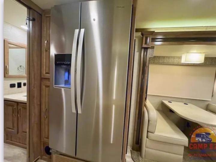 Spacious RV rental interior with a large stainless steel fridge, dinette, and bathroom visible on the left.. Jayco Seneca 2020