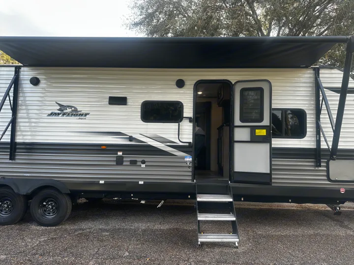 Jay Flight RV rental: a modern travel trailer with extended awning, open door, and steps, perfect for camping.. Jayco Jay Flight 2024