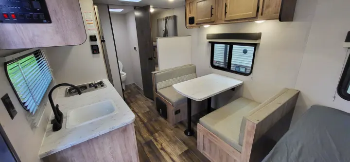 Spacious RV rental interior featuring a modern kitchenette, comfortable dinette, and cozy sleeping area. Ideal for travel.. Gulf Stream Ameri-Lite 2024