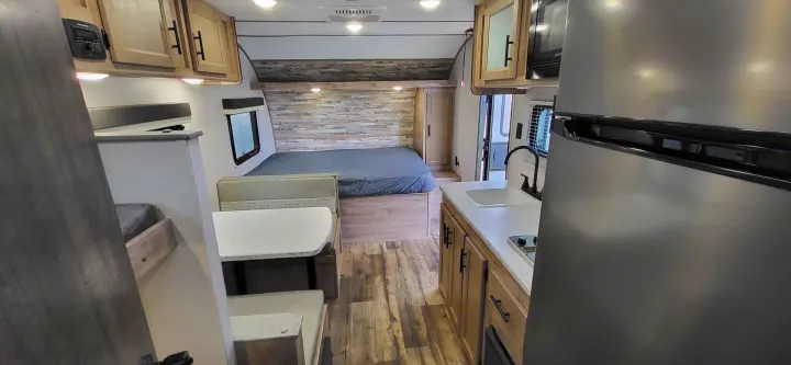 Step inside this modern RV rental: a compact interior featuring a full bed, dinette, and kitchen. Ideal for road trips.. Gulf Stream Ameri-Lite 2024