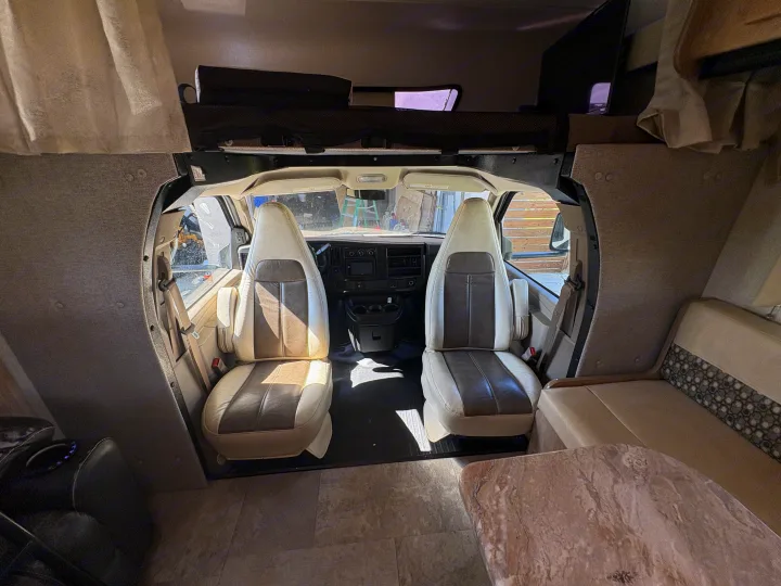 Explore this RV rental's inviting interior: the cockpit features two captain's chairs, an overhead bunk, and a mounted TV.. Coachman Leprechaun 2019