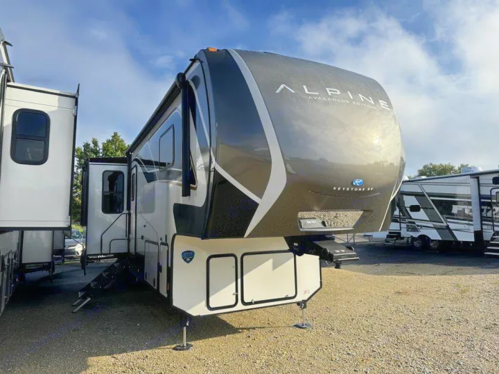 Modern Alpine fifth-wheel recreational vehicle, ready for rv rental. White, black, and gray camper with slide-outs extended.. Keystone Alpine 2025