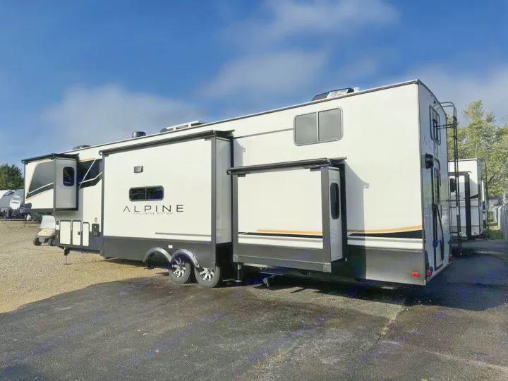 White Alpine Avalanche Edition fifth-wheel RV rental with extended slide-outs. Parked outdoors in a sunny lot.. Keystone Alpine 2025