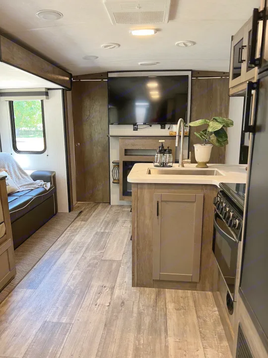 Step inside this inviting RV rental. A modern interior features a well-equipped kitchen, comfy living area, and TV setup.. Heartland RVs North Trail 2021