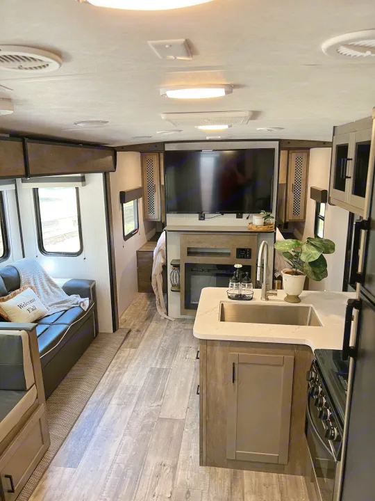 This cozy rv rental interior offers a full kitchen, comfortable living area with sofa, fireplace, and flat-screen TV.. Heartland RVs North Trail 2021