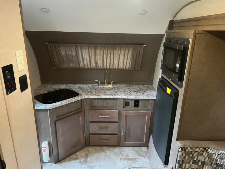 RV rental kitchen: modern, compact space with sink, stove, microwave, fridge, and storage.. Forest River R-Pod 2018