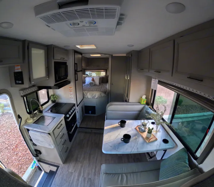 Spacious and modern RV rental interior with a full kitchen, comfortable dining area, and a private bedroom.. Thor Coleman 2024