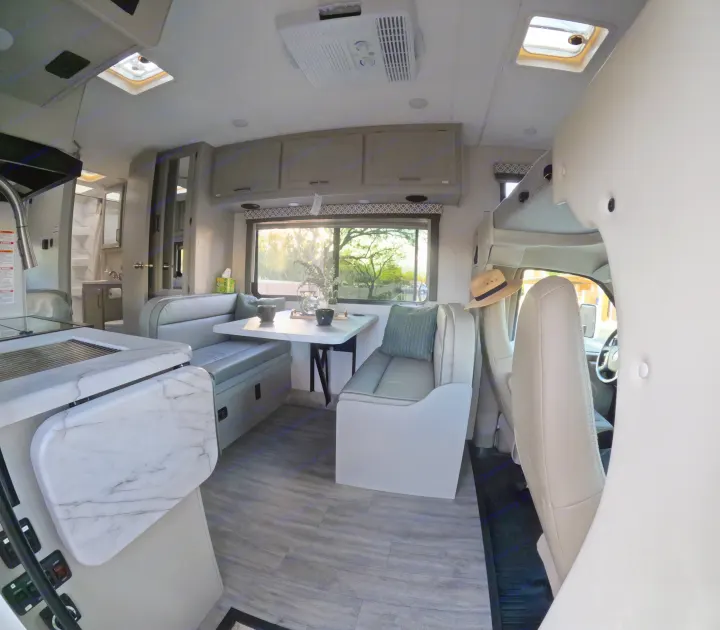Inside a modern RV rental: a spacious dinette, kitchen, and bright windows for your next adventure.. Thor Coleman 2024