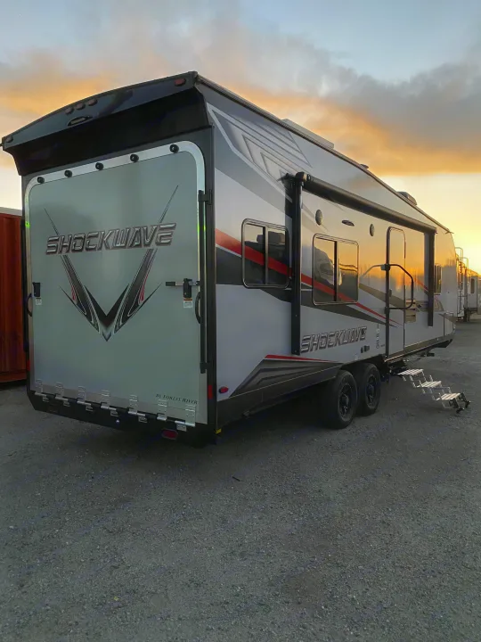 Ready for adventure: a sleek grey and black toy hauler RV at sunset, ideal for your next rv rental getaway.. Forest River Shockwave 2021
