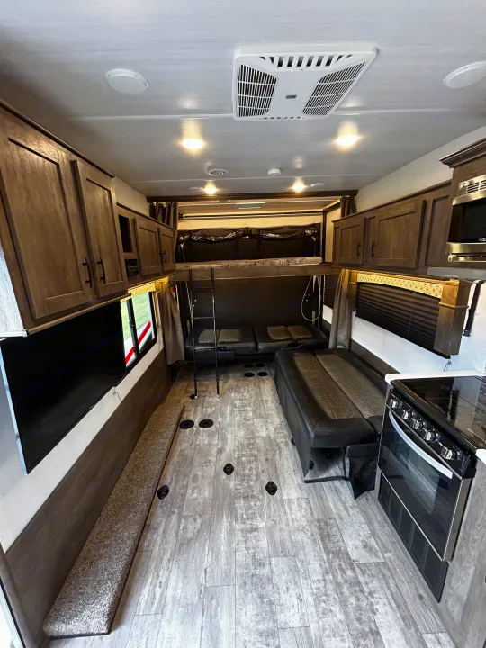 Spacious RV rental interior with bunk beds, convertible sofas, kitchen, TV, and wood-look flooring. Ready for adventure!. Forest River Shockwave 2021