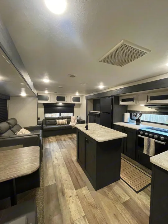Modern RV rental interior featuring a full kitchen with island, cozy living room sofas, and dining space for a comfortable journey.. KZ Sportsmen 2022