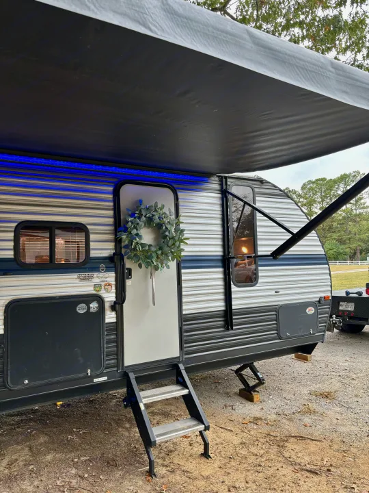 Cozy rv rental: a travel trailer parked with an extended awning, blue LED lights, and a decorative wreath on the door.. Forest River Cherokee Grey Wolf 2019
