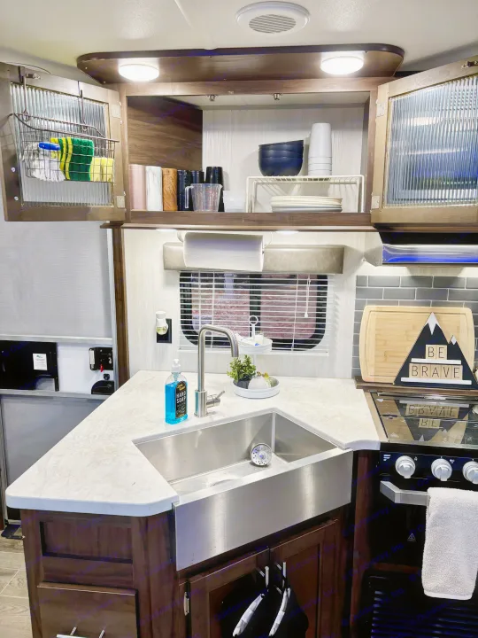 Spacious RV rental kitchen with a large stainless steel sink, modern faucet, oven, and organized cabinets.. Forest River Cherokee Grey Wolf 2019