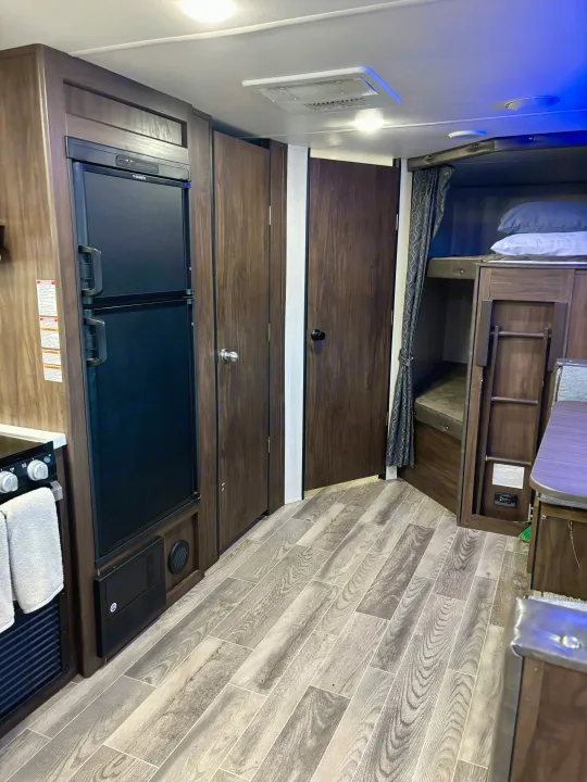 Inside an RV rental: view of kitchen with Dometic fridge, storage doors, bunk beds, and compact living space.. Forest River Cherokee Grey Wolf 2019