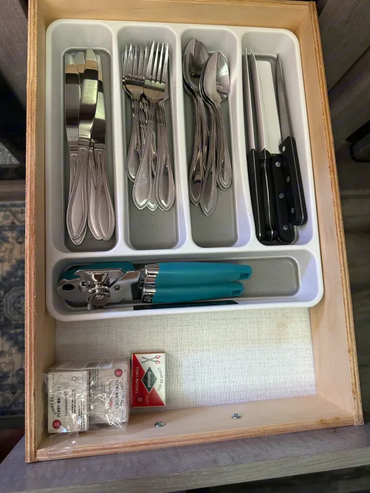 RV rental kitchen drawer with an organized utensil organizer containing silverware, knives, a can opener, and matches.. Coleman Lantern 17b 2024