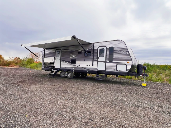 Explore the outdoors! This modern Jay Flight travel trailer, with awning extended, makes for a perfect rv rental on gravel.. Jayco Jayflight 2021