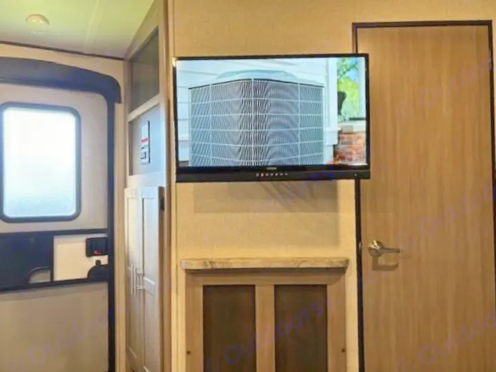 RV rental interior: a wall-mounted TV over a cabinet, an entry door with window, and a closed interior door.. Crossroads Sunset Trail Super Lite 2022