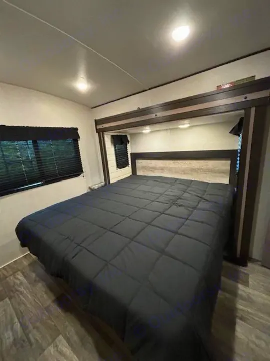 Comfortable RV rental bedroom featuring a large bed, overhead storage, and window with blinds.. Crossroads Sunset Trail Super Lite 2022