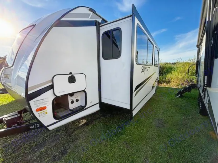 Spacious rv rental: A white Sunset Trail travel trailer with extended slide-out, parked on grass under a clear sky.. Crossroads Sunset Trail Super Lite 2022