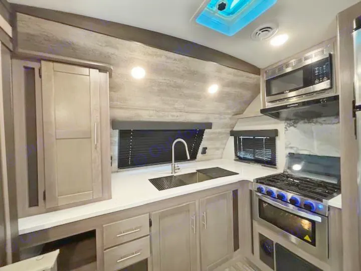Modern RV rental kitchen with stainless steel stove, oven, microwave, and sink. Features ample cabinets and bright lighting.. Crossroads Sunset Trail Super Lite 2022