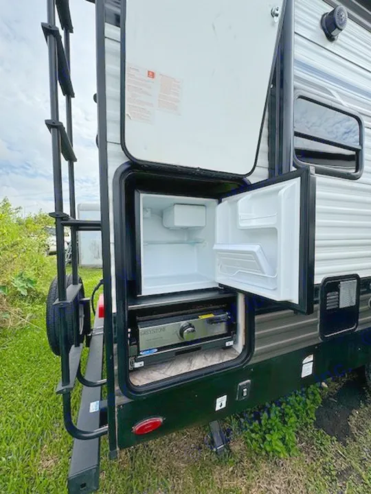 RV rental: Exterior view of an outdoor kitchen with an open mini-fridge and a Greystone grill.. Palomino Puma 2023